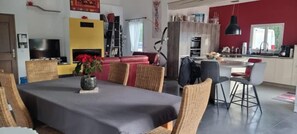 Un espace de vie moderne comprenant un coin repas, une cuisine et un mur d’accent rouge.