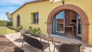 A yellow building with a patio area featuring outdoor furniture and a brick archway.