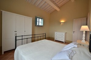 Une chambre à coucher comprenant un lit, une armoire, une table de chevet, une lampe et une fenêtre.