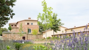 A building with a stone facade, a flat roof, and a garden with lavender. - Hotel Apartment "Quercia" with Shared Pool & Wi-Fi (Trequanda)