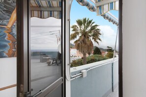 A balcony with a view of the sea, a palm tree, and a building in the background. - Vacation Studio 'La Zotea' with Mountain View and Wi-Fi (Tegueste)
