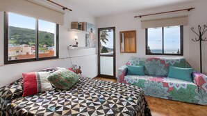 A bedroom with a bed, a sofa, large windows, a view of the sea, and a balcony. - Vacation Studio 'La Zotea' with Mountain View and Wi-Fi (Tegueste)