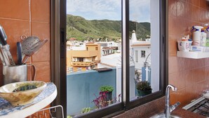 A kitchen with a window view of a town, a sink, and a countertop with kitchen utensils. - Vacation Studio 'La Zotea' with Mountain View and Wi-Fi (Tegueste)