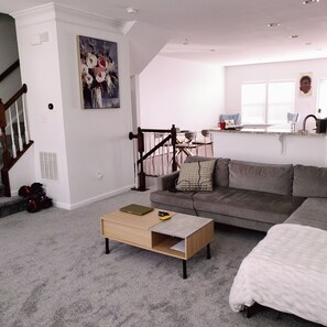 A living room with a sofa, a coffee table, and a staircase. - HiddenParadise in Scenic community, mins to attractions & WaterFront. Sleeps 9 (Glen Burnie)