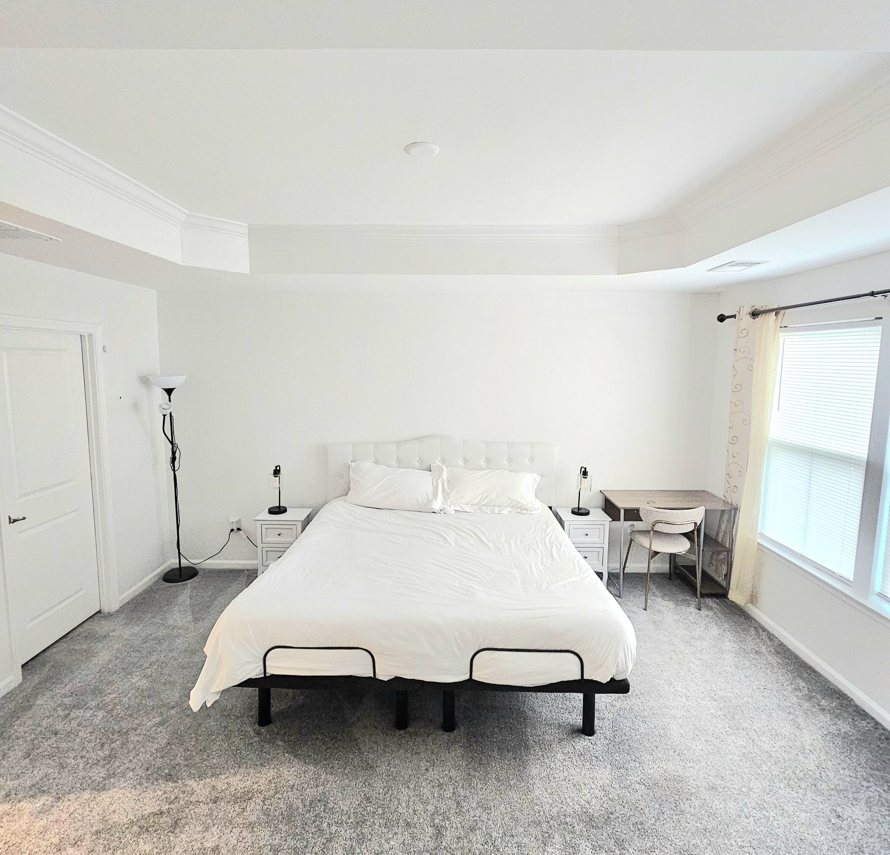 Un dormitorio con cama, escritorio, silla y dos mesitas de noche.