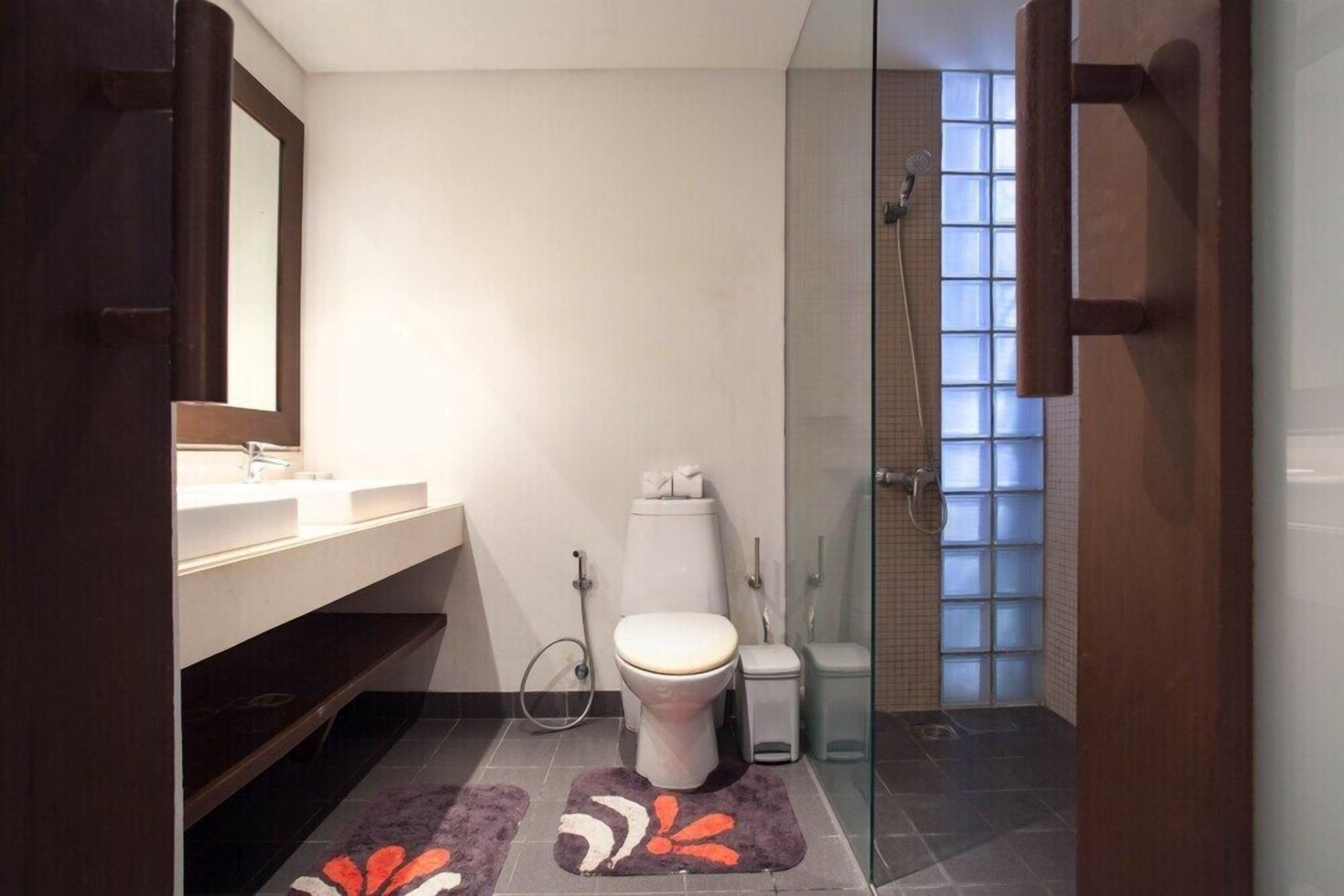 Un baño moderno con cabina de ducha de vidrio, inodoro blanco y tocador con espejo.