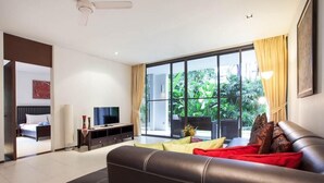 A modern living room with a large window, a sofa, a TV, and a dining area with a table and chairs.