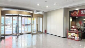 A hotel entrance with a revolving door, a glass storefront, and a fire extinguisher near the door. - Kocemo Hotel (Yanji)