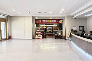 A hotel lobby with a reception desk, a food counter, and a tiled floor. - Kocemo Hotel (Yanji)