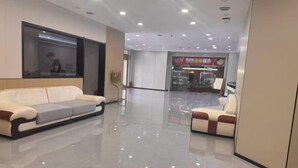 A modern hotel lobby with a glass partition, a sofa, a chair, and a reception desk. - Kocemo Hotel (Yanji)