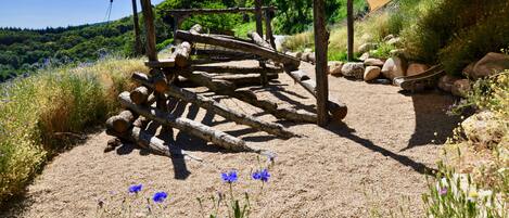 A rustic outdoor area with a wooden structure, gravel path, and wildflowers.
