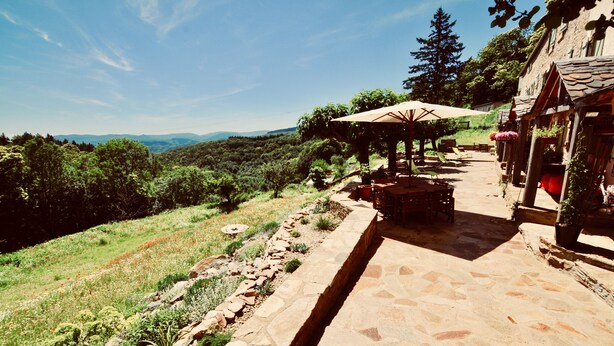 Un espace extérieur aménagé en terrasse, avec un sol en pierre, des sièges et une vue sur le paysage environnant.