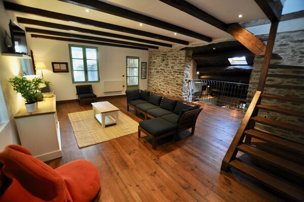 A cozy living room with a wooden floor, a sofa, a coffee table, and a staircase leading to an upper level.