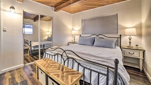 Een slaapkamer met een bed, nachtkastjes, een spiegel en een houten bankje.