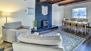 Een woonkamer met een open haard, een eethoek met houten stoelen en een groot raam.