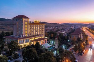 Un hotel de varios pisos con una torre central destacada, una fachada bien iluminada y vistas a una calle con vehículos.