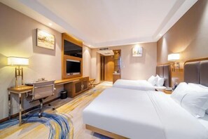 A hotel room with a bed, desk, chair, TV, and artwork on the walls. - Botai Hotel (Qujing)