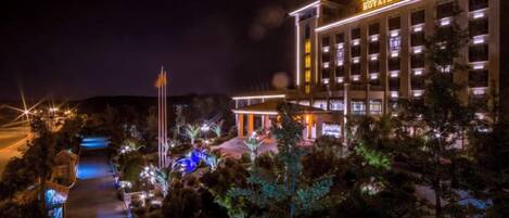A hotel with multiple floors, a well-lit entrance, and a pathway leading to the building.