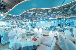 Un restaurante con mesas redondas, sillas blancas y un techo con diseño ondulado.