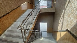 Un escalier avec des rampes en métal, des marches blanches et une vue sur l’espace intérieur.
