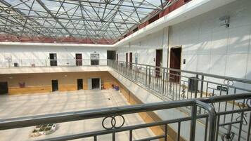 A spacious indoor area with a high ceiling and a glass roof, featuring multiple doors and a central open space.