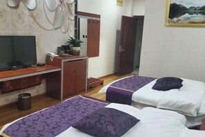 Une chambre d’hôtel avec deux lits, un bureau avec une télévision, une armoire et une porte de salle de bain.