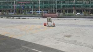Un parking avec une surface en béton, des emplacements de stationnement délimités et quelques cônes de signalisation.