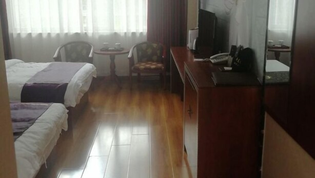 Habitació d'hotel amb dos llits, una taula rodona petita, una cadira, una televisió i un escriptori amb un telèfon.