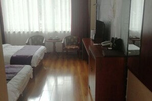 A hotel room with two beds, a small round table, a chair, a television, and a desk with a telephone. - Kangma Weinasi Hotel (Kangma)