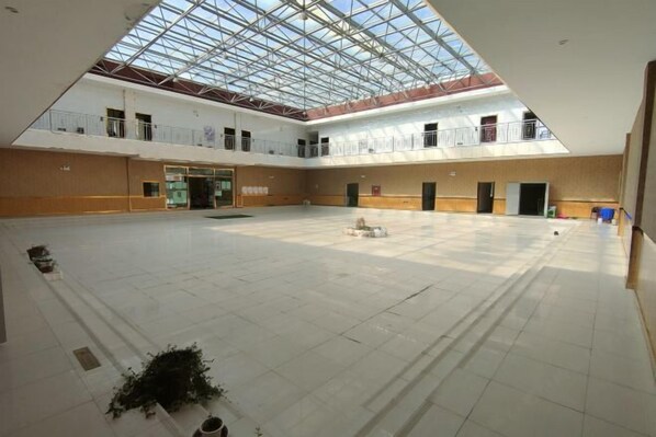 A spacious indoor area with a high ceiling and skylights, featuring a central open space and multiple doorways leading to other rooms. - Kangma Weinasi Hotel (Kangma)