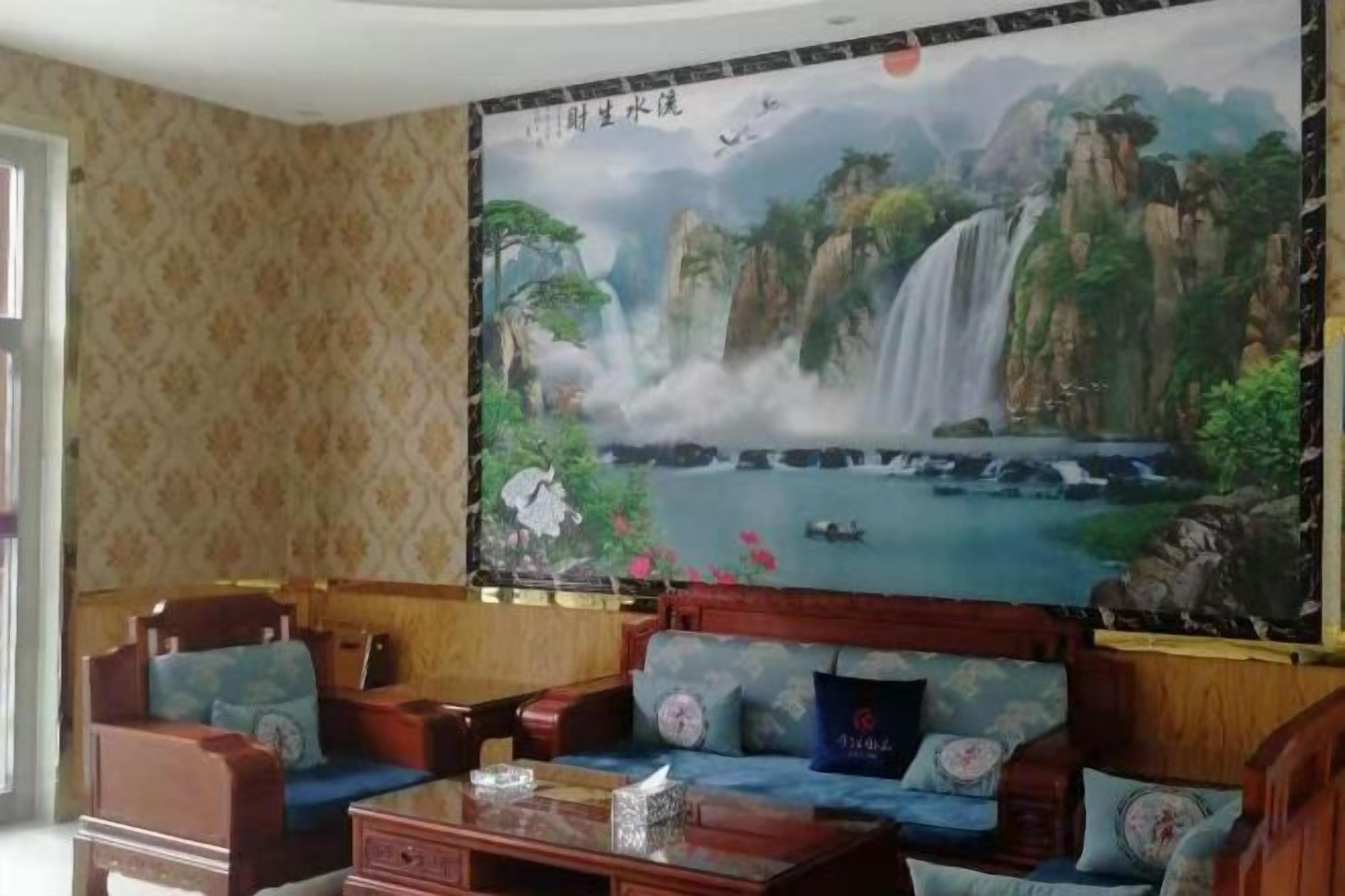 Una habitación con un sofá tradicional, una mesa de centro de madera y un gran mural de una cascada en la pared.