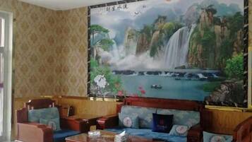 Una habitación con un sofá tradicional, una mesa de centro de madera y un gran mural de una cascada en la pared.
