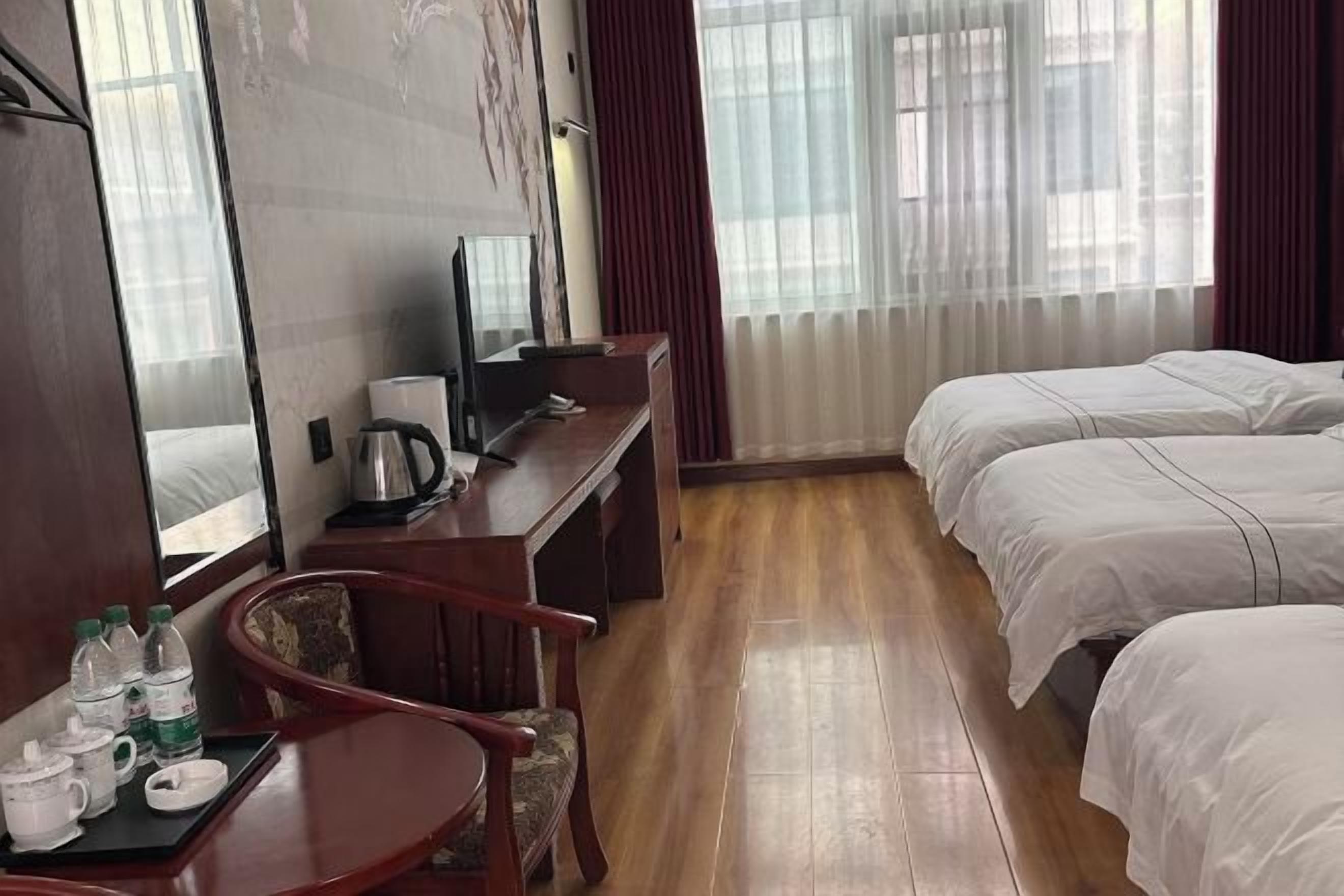 A hotel room with a wooden desk, a bed, and a TV.
