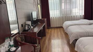 A hotel room with a wooden desk, a bed, and a TV.