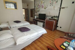 Une chambre d’hôtel comprenant un lit, un bureau avec une télévision, une petite table avec un plateau, et un mur décoratif.
