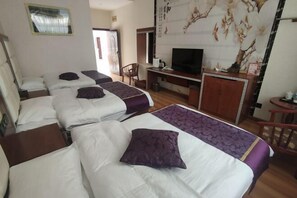 Une chambre d’hôtel avec trois lits, une télévision et un bureau avec un ordinateur.