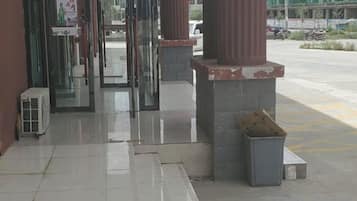 A building entrance with glass doors, a trash bin, and a clear view of the street outside.