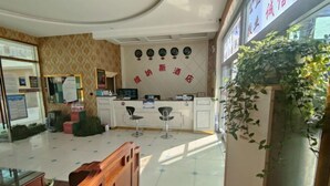 Un hall d’hôtel comprenant un comptoir d’accueil, un espace salon et un mur décoratif orné d’horloges.