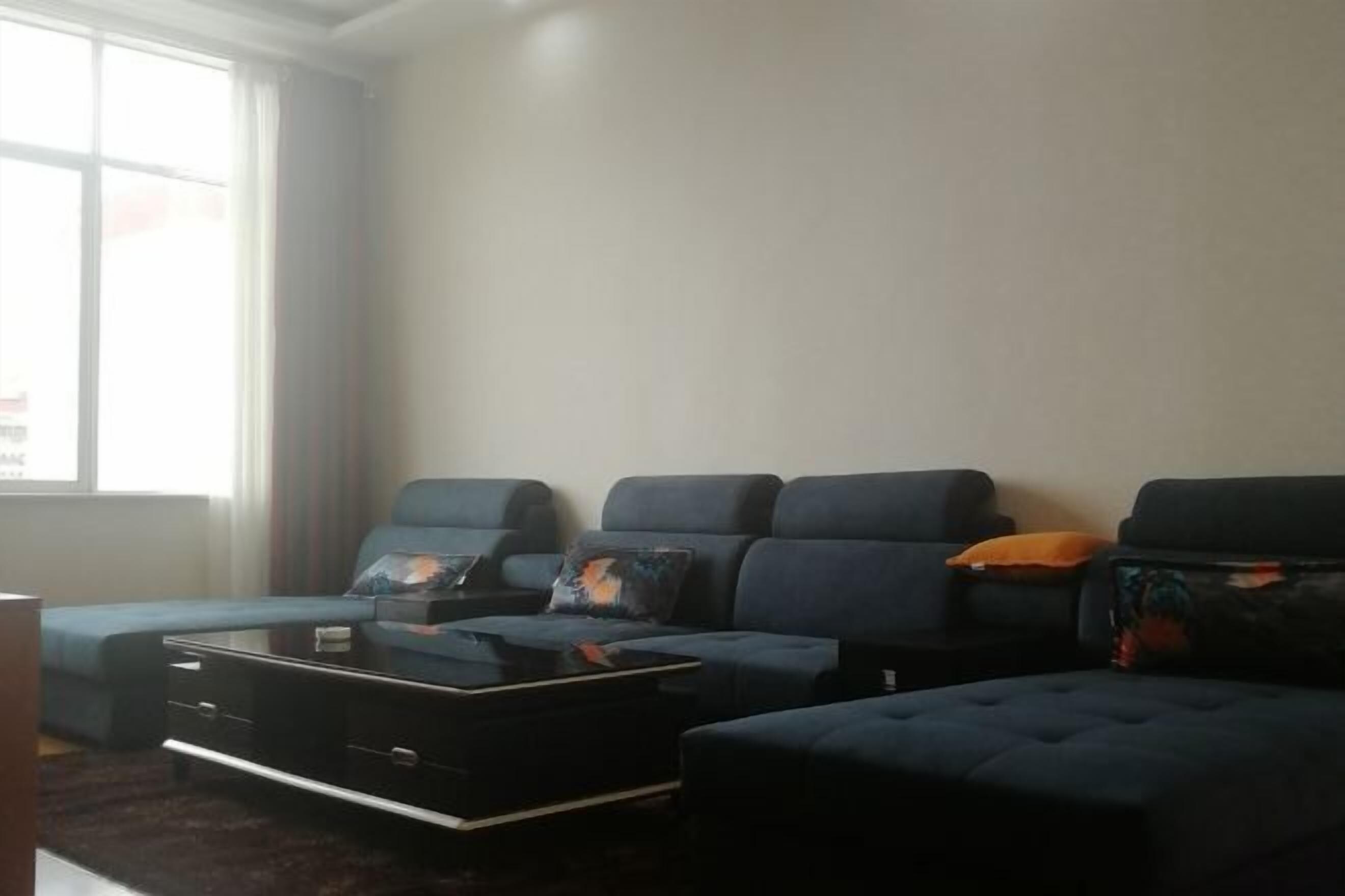 A living room with a sectional sofa, a coffee table, and a window with curtains.