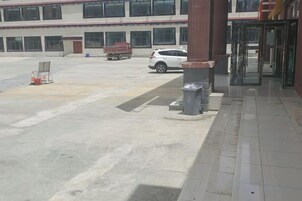 A building entrance with a paved driveway, a turnstile, and a parked white vehicle.