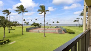 A tennis court surrounded by palm trees, with a view of the ocean. - Maui Sunset Vacation Rentals A419 (Kihei)
