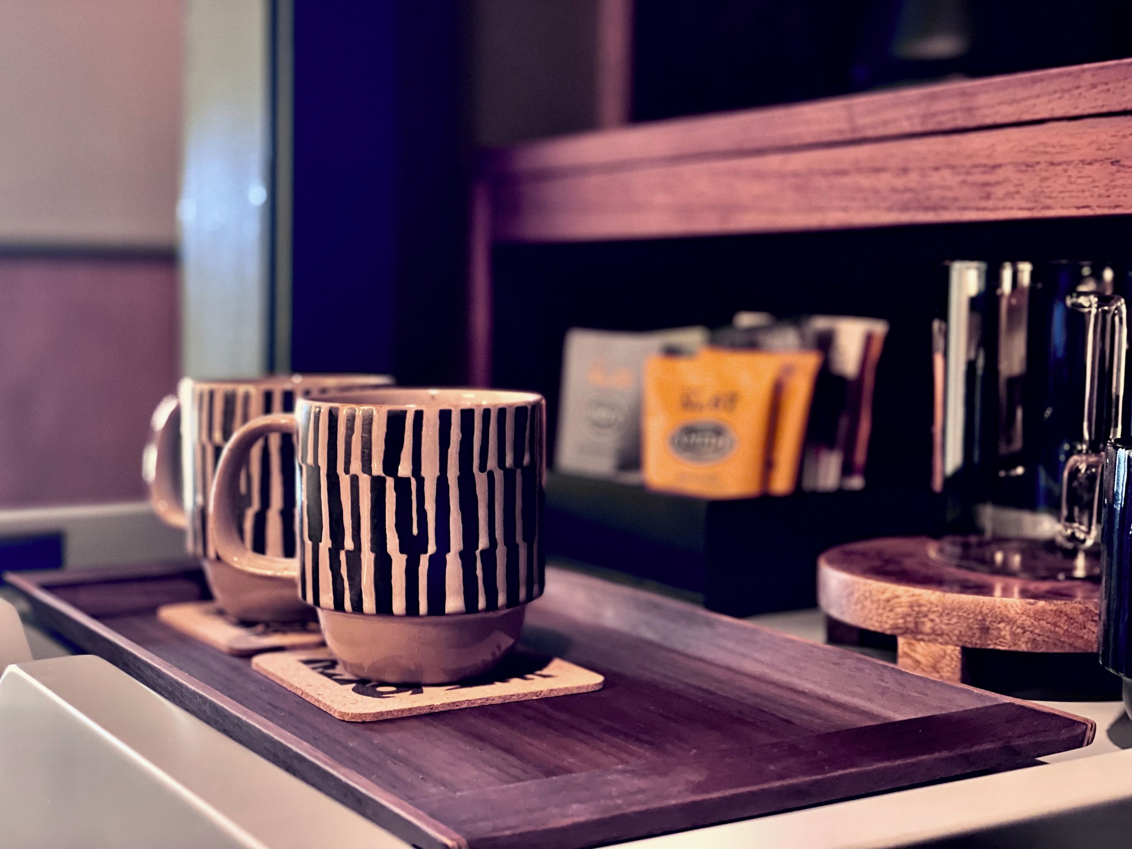 A wooden tray with three mugs and a coffee machine.