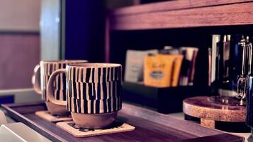 A wooden tray with three mugs and a coffee machine.