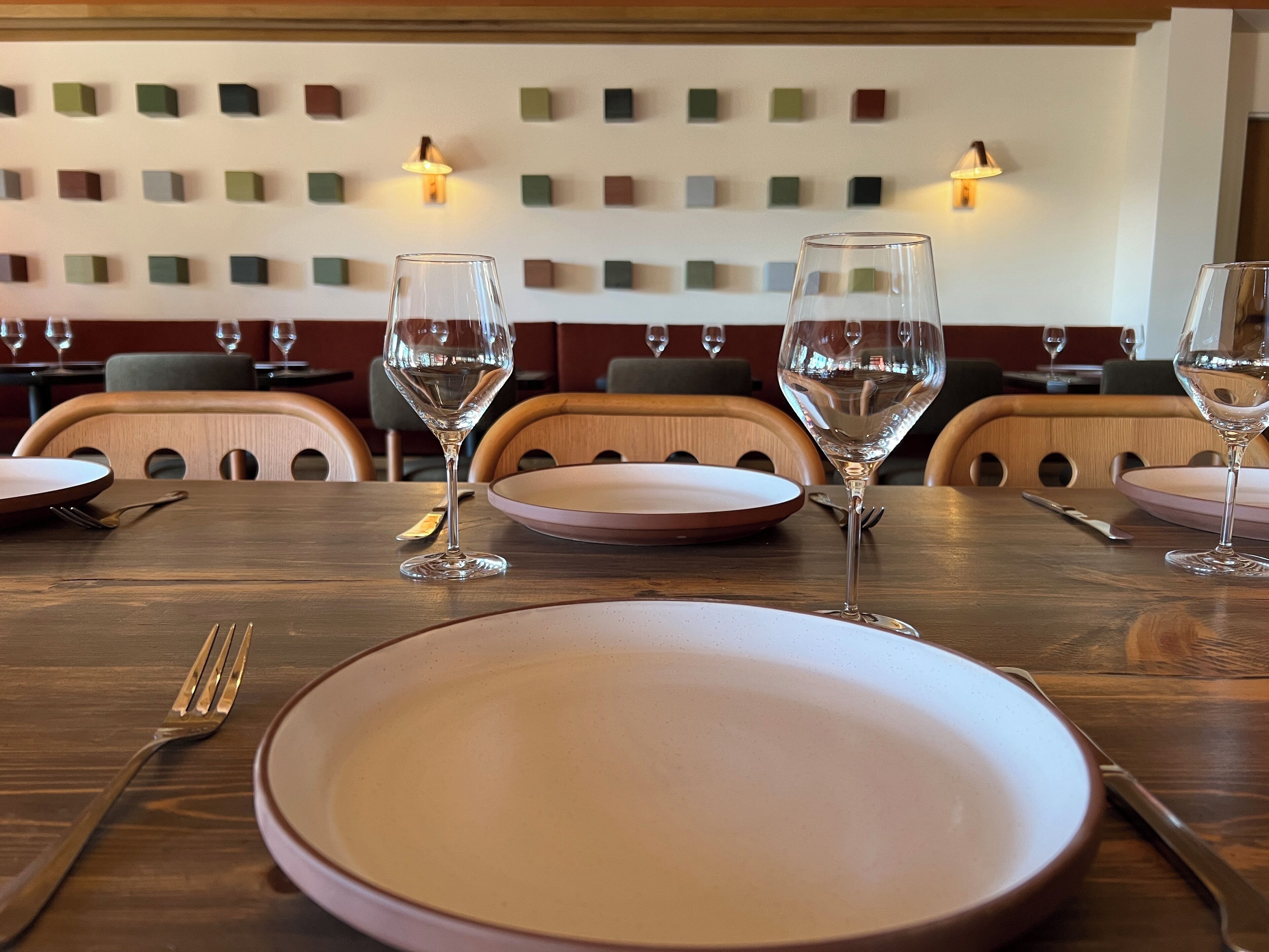 Ein Restaurant mit gedeckten Tischen, darunter Teller, Besteck und Weingläser.