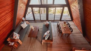 Een gezellig, houten interieur met een groot raam dat uitkijkt op een terras.