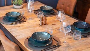 A dining table set with plates, glasses, and cutlery, with hanging light fixtures above. - TIMANA: La Bodega - Design Apartment nähe der Alster (Hamburg)