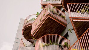 Un edificio de varios pisos con balcones que lucen barandillas de madera y macetas con plantas.