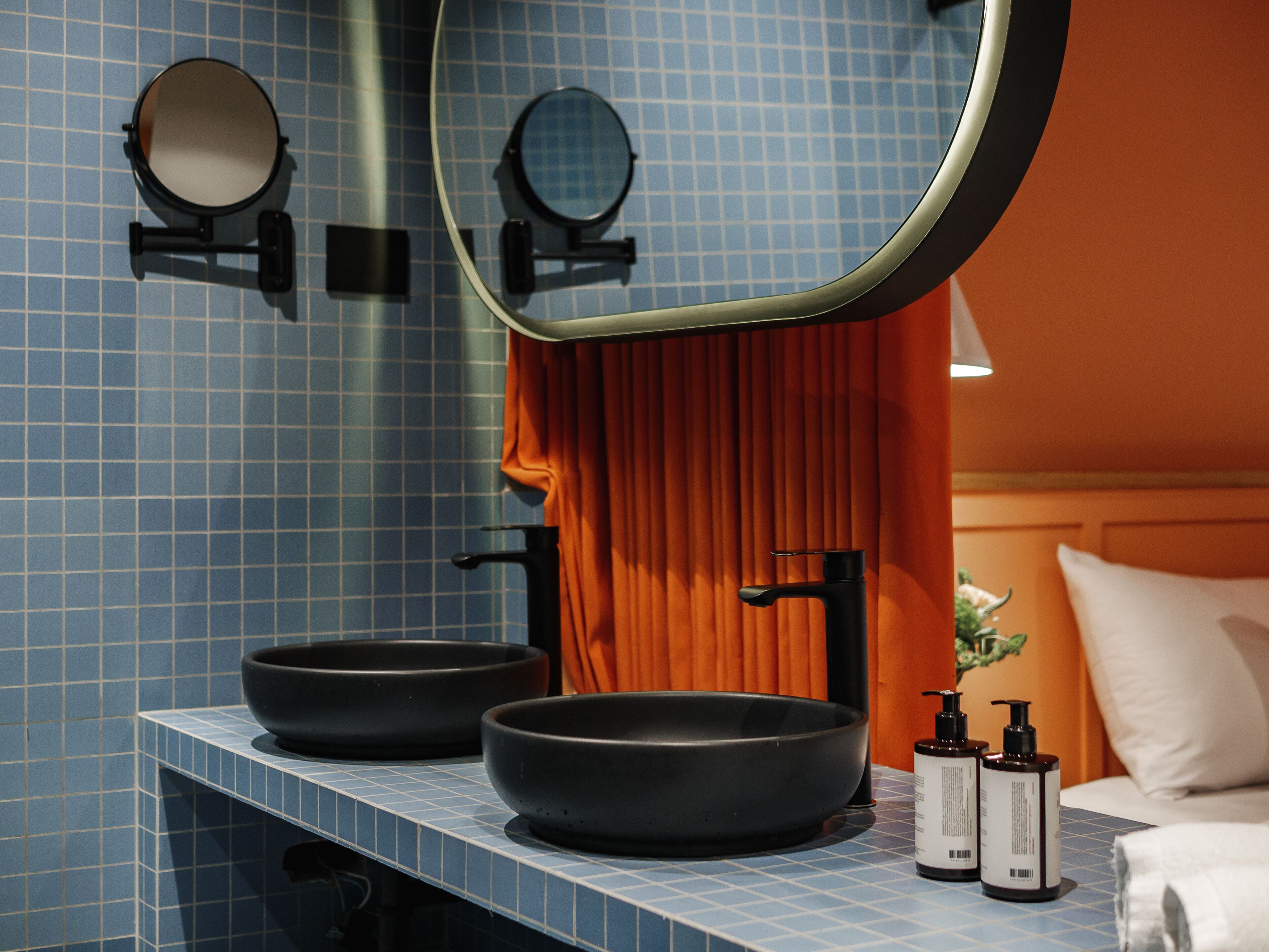 A bathroom with two black sinks, a mirror, and two bottles of shampoo.