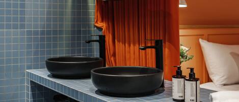 A bathroom with two black sinks, a mirror, and two bottles of shampoo.