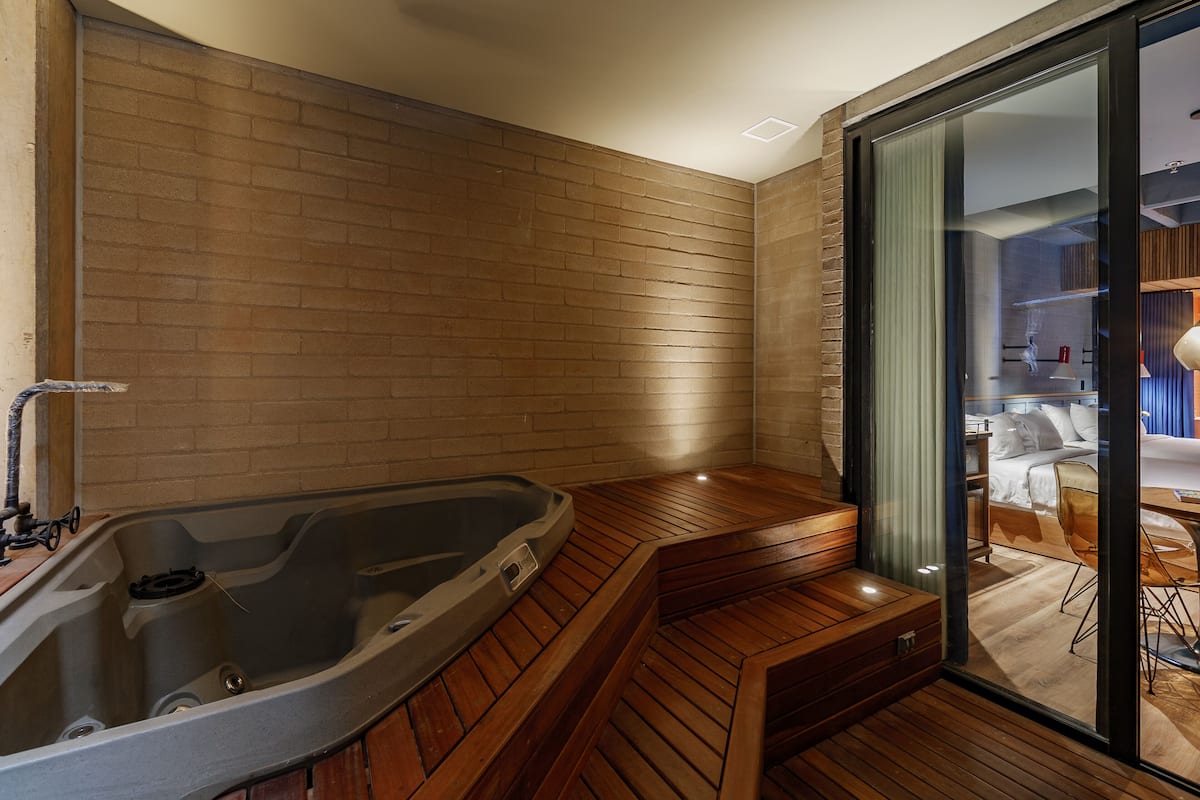 A modern bathroom with a wooden bench, a bathtub, and a glass shower enclosure.